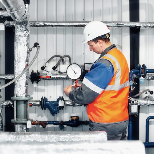 operador-caldera-gas-casco-chaleco-comprueba-lecturas-presion-manometros-produccion